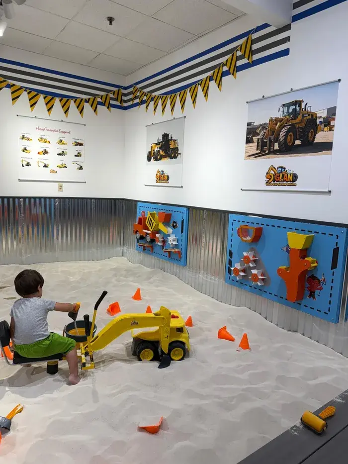 A young child digging with a toy excavator, developing motor skills